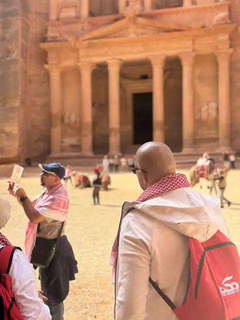 Pèlerins du groupe devant Al-Khazneh à Pétra, keffiehs et sacs rouges