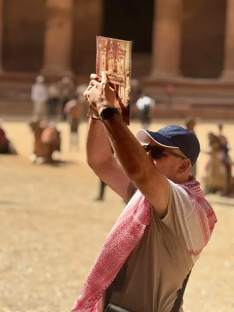 Visiteur en keffieh tenant un souvenir représentant le Trésor de Pétra, Jordanie