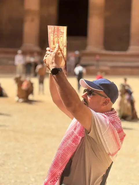 Le guide lève une illustration colorée pour présenter un monument au groupe, sur l'esplanade du Mont du Temple à Jérusalem.