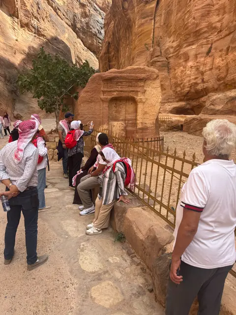 Groupe de visiteurs devant les tombeaux nabatéens de Petra, falaises de grès rouge en arrière-plan