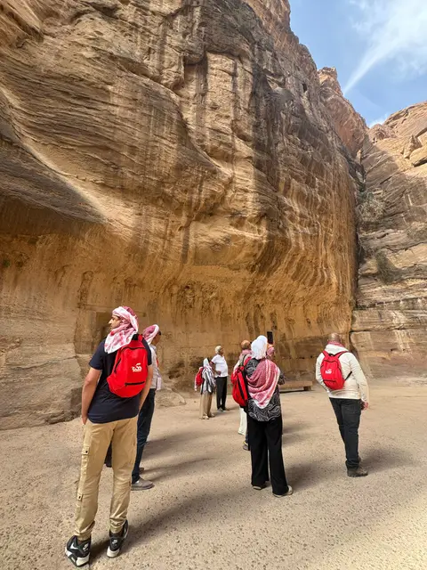 Groupe de voyageurs se promenant dans le siq de Pétra aux falaises de grès ocre