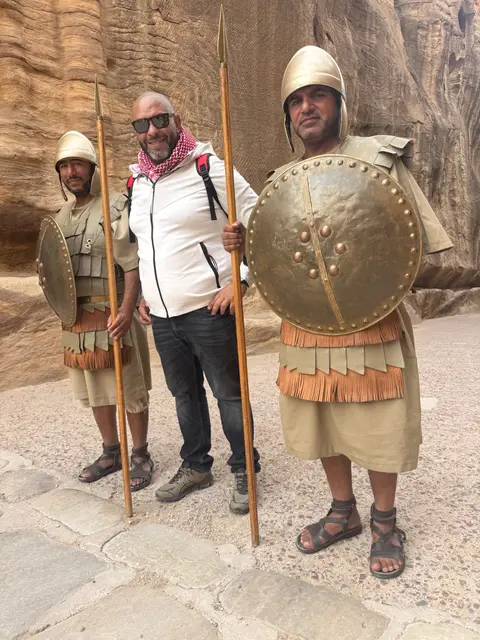 Voyageur posant avec deux acteurs en costumes de soldats nabatéens dans le siq de Pétra
