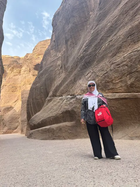 Voyageuse posant dans le siq de Pétra entre deux hautes falaises de grès rouge