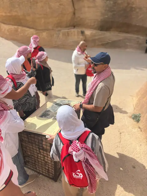 Groupe de voyageurs écoutant un guide devant un panneau informatif sur un site historique
