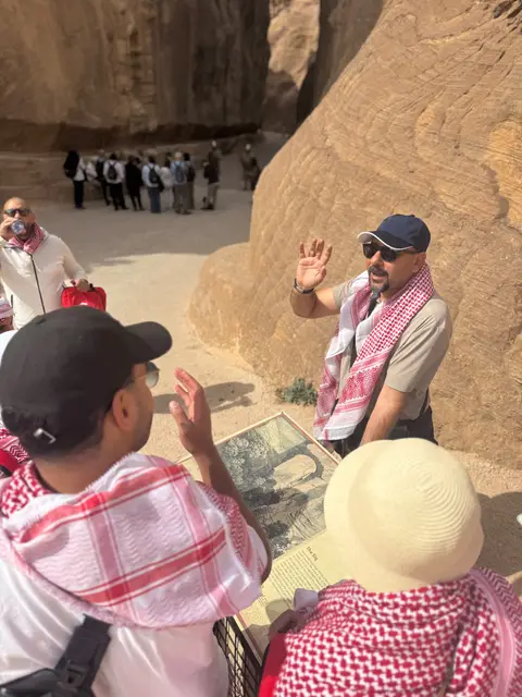 Guide expliquant un site archéologique désertique à un groupe de voyageurs