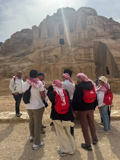 Groupe en visite devant les tombeaux nabatéens taillés dans la falaise à Madain Saleh