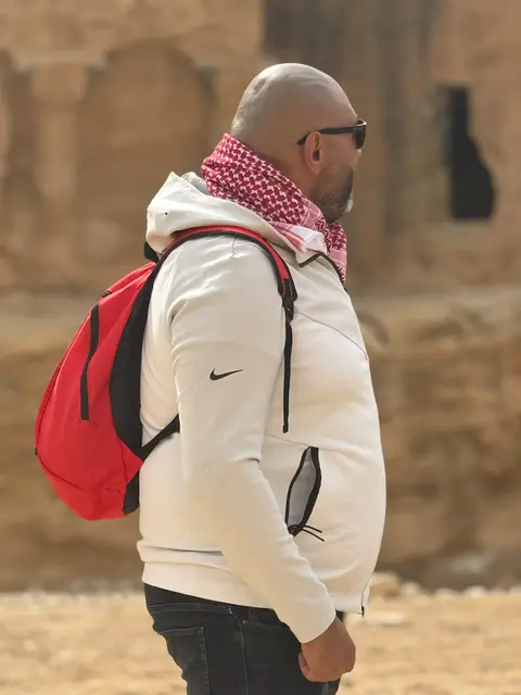 Voyageur en foulard traditionnel devant des ruines de pierre dans un cadre désertique