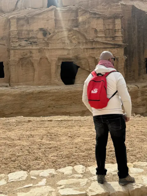 Voyageur contemplant des façades rupestres sculptées dans la pierre sur un site archéologique