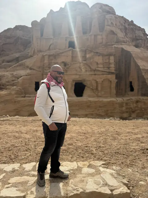 Voyageur posant devant un tombeau taillé dans la roche à Pétra, Jordanie
