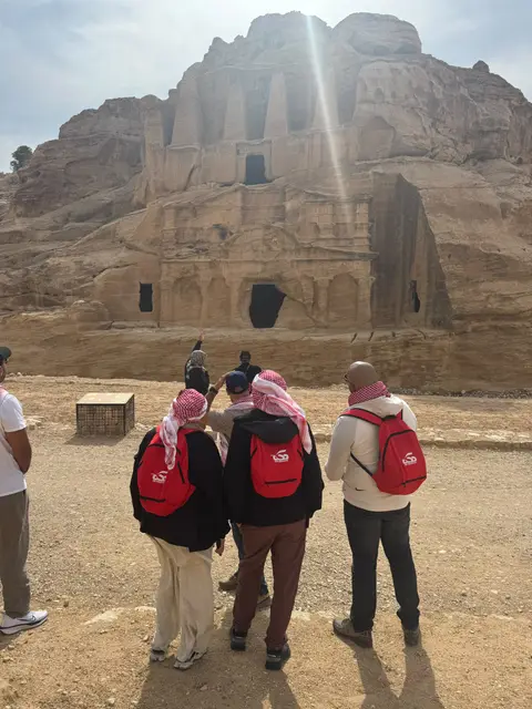 Visiteurs contemplant une grande façade sculptée dans le grès à Pétra, Jordanie
