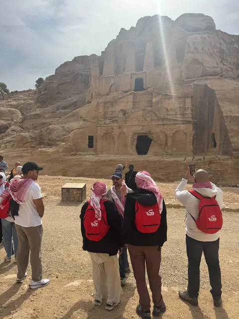 Groupe de voyageurs devant un tombeau nabatéen creusé dans la roche à Pétra, Jordanie