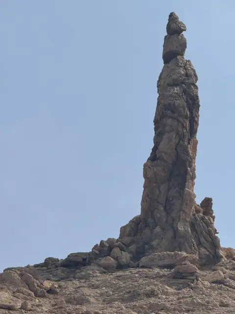 Imposant monolithe rocheux naturel se dressant dans le désert sous un ciel bleu