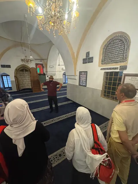 Visite guidée à l'intérieur d'une mosquée historique, groupe de pèlerins écoutant le guide