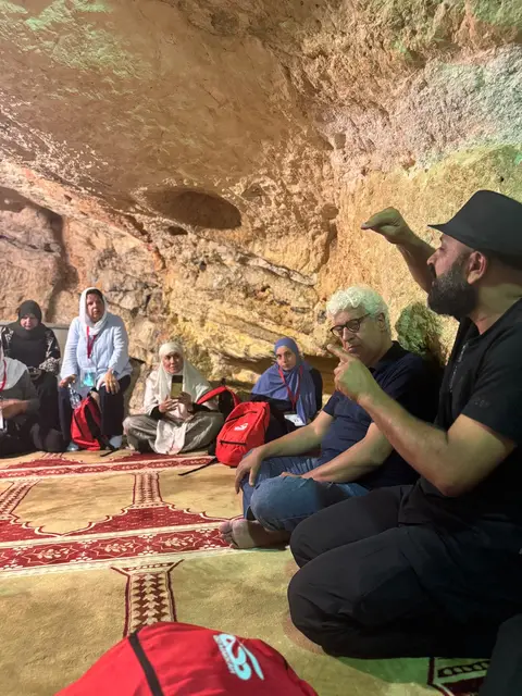 Groupe de pèlerins en écoute recueillie dans une grotte historique de Jérusalem