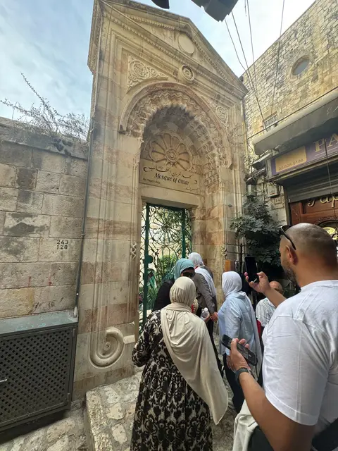 Pèlerins franchissant la porte ornementale historique de la Mosquée Al-Umar à Jérusalem