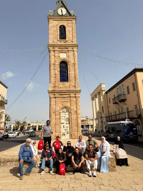 Groupe de voyageurs posant devant la tour de l'horloge de Jaffa, Israël