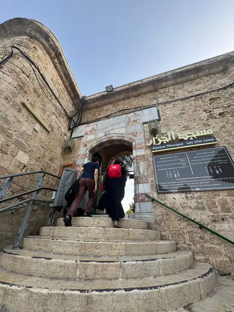 Entrée de la mosquée Al-Jazar à Akko, deux visiteurs gravissant les marches en pierre