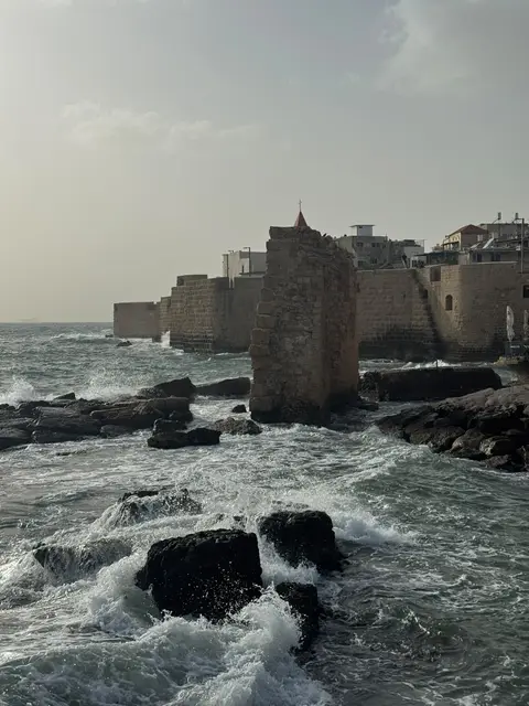 Remparts en pierre au bord de la mer avec vagues et vieille ville en arrière-plan